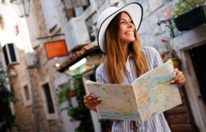Smiling tourist woman with a map sightseeing a historic city.