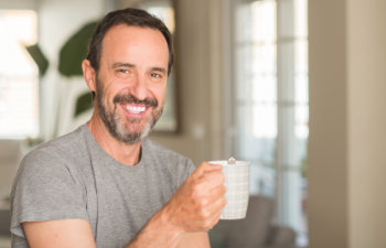 mature smiling man holding a coffee cup and smiling