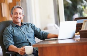 mature man smiling drinking coffee at the desk